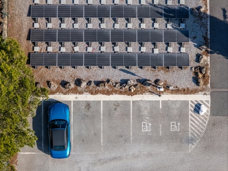 Aerial view of a blue electric car parked in a charging station next to a solar panel array in Cascais Lisboa Portugal. Aerial view of a blue electric car parked in a charging station next to a solar panel array in Cascais Lisboa Portugal.