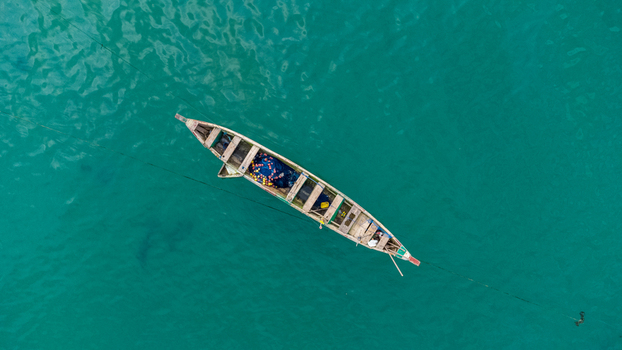 Axim Western Region Ghana 09 February 2023 Aerial view of a traditional wooden fishing boat floating on the turquoise waters near the coast of the Lou Moon Resort. Axim Western Region Ghana 09 February 2023 Aerial view of a traditional wooden fishing boat floating on the turquoise waters near the coast of the Lou Moon Resort.