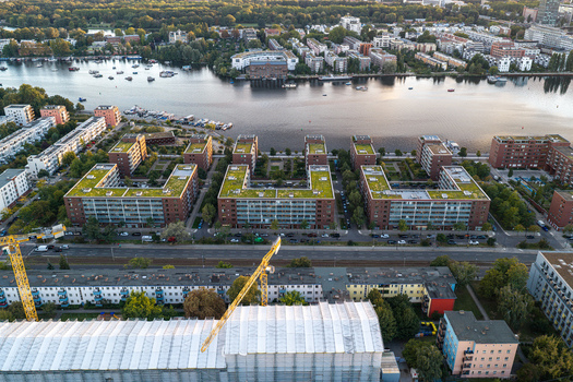 Aerial view of the Schlichtallee residential complex featuring modern U shaped buildings with green roofs situated near the Spree river with construction cranes in Berlin Berlin Germany. Aerial view of the Schlichtallee residential complex featuring modern U shaped buildings with green roofs situated near the Spree river with construction cranes in Berlin Berlin Germany.