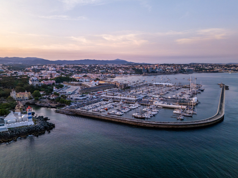 Aerial view of the marina with numerous sailboats and yachts docked near the Santa Marta Lighthouse overlooking the coastal town of Cascais Lisboa Portugal. Aerial view of the marina with numerous sailboats and yachts docked near the Santa Marta Lighthouse overlooking the coastal town of Cascais Lisboa Portugal.