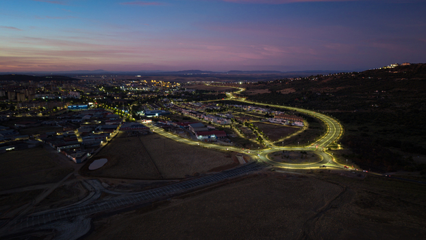 Aerial view of the illuminated roundabout and urban landscape at dusk featuring glowing streetlights and residential buildings in Caceres Extremadura Spain.