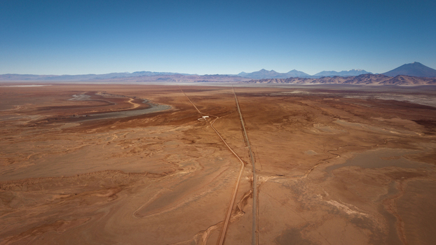 Aerial view of the vast arid desert landscape with a long straight road stretching towards the distant mountains in Tolar Grande Salta Province Argentina. Aerial view of the vast arid desert landscape with a long straight road stretching towards the distant mountains in Tolar Grande Salta Province Argentina.
