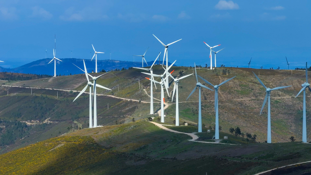 Aerial view of a wind farm with multiple white wind turbines situated on rolling green hills under a clear blue sky in Lisbon Lisbon Portugal. Aerial view of a wind farm with multiple white wind turbines situated on rolling green hills under a clear blue sky in Lisbon Lisbon Portugal.