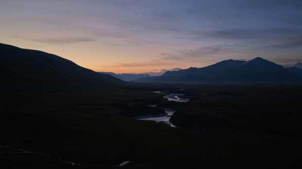 Aerial view of the winding river flowing through the mountainous landscape near Engilchek Glacier at dusk in Ak Su Issyk Kul Region Kyrgyzstan. Aerial view of the winding river flowing through the mountainous landscape near Engilchek Glacier at dusk in Ak Su Issyk Kul Region Kyrgyzstan.
