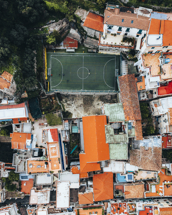 Aerial view of a soccer field surrounded by vibrant orange roofed buildings and lush green trees Positano Italy. Aerial view of a soccer field surrounded by vibrant orange roofed buildings and lush green trees Positano Italy.