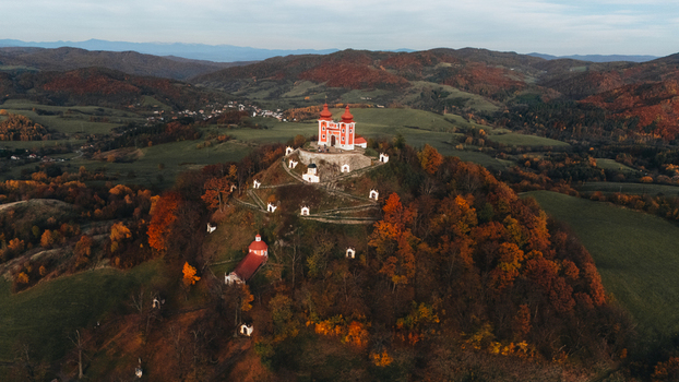 Aerial view of Kalvaria Banska Stiavnica with its red roofed chapels on a hilltop surrounded by vibrant autumn foliage and rolling hills in Banska Stiavnica Banskobystricky kraj Slovakia.