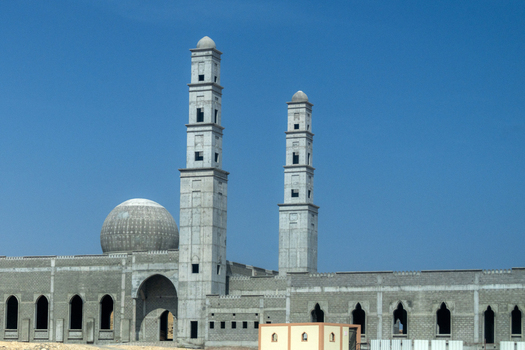 View of a mosque under construction with two tall minarets and a dome against a clear blue sky in Muscat Muscat Governorate Oman. View of a mosque under construction with two tall minarets and a dome against a clear blue sky in Muscat Muscat Governorate Oman.