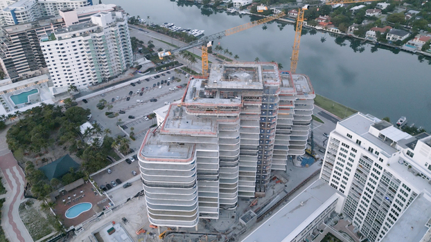 Aerial view of a large residential building under construction with cranes surrounding high rise apartments a canal and parking areas in Miami Beach Florida United States. Aerial view of a large residential building under construction with cranes surrounding high rise apartments a canal and parking areas in Miami Beach Florida United States.