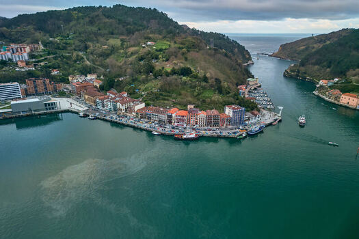 Pasai Donibane Spain 10 March 2026 Aerial view of the Harbour mouth of Pasaia with colorful waterfront buildings docked boats and lush green hills under a cloudy sky. Pasai Donibane Spain 10 March 2026 Aerial view of the Harbour mouth of Pasaia with colorful waterfront buildings docked boats and lush green hills under a cloudy sky.