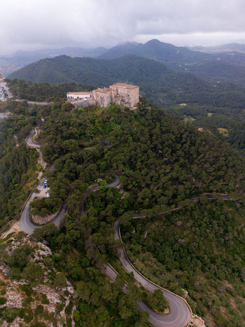 Aerial view of the Sanctuary of Sant Salvador on a hilltop with a winding road through the forest in Felanitx Illes Balears Spain. Aerial view of the Sanctuary of Sant Salvador on a hilltop with a winding road through the forest in Felanitx Illes Balears Spain.