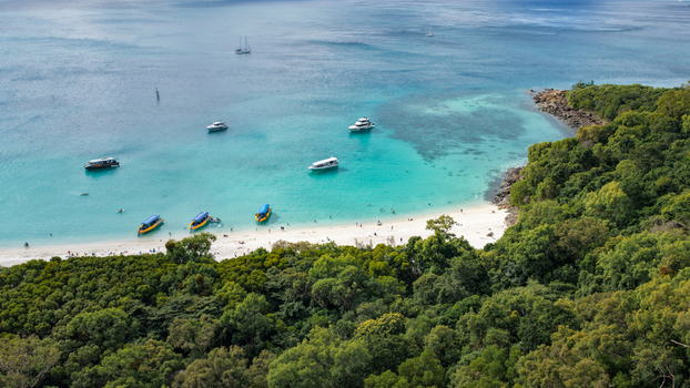 Aerial view of Whitehaven Beach featuring turquoise waters white sand and several boats anchored near the lush tropical forest in Whitsundays Queensland Australia.