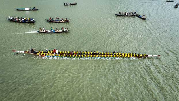Baghabari Rajshahi Division Bangladesh 20 August 2022 Aerial view of a traditional long boat race with rowers in yellow shirts paddling in unison on the river.
