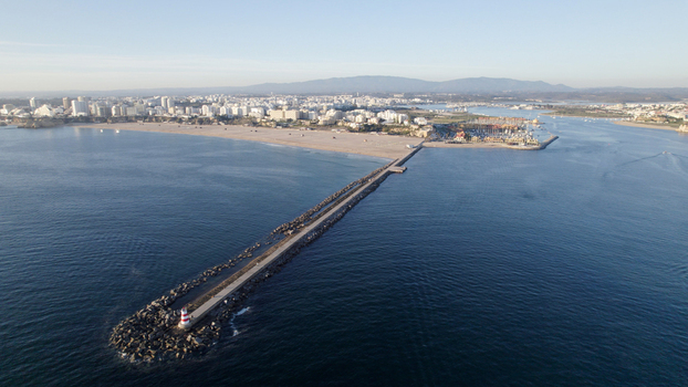 Aerial view of the breakwater and lighthouse at Praia da Rocha with the sandy beach marina and urban coastline in the background in Faro District Portugal.