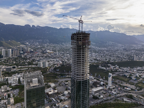 Aerial view of Rise Tower under construction with a tall crane on top surrounded by the urban skyline and mountains in the background Monterrey Nuevo Leon Mexico. Aerial view of Rise Tower under construction with a tall crane on top surrounded by the urban skyline and mountains in the background Monterrey Nuevo Leon Mexico.