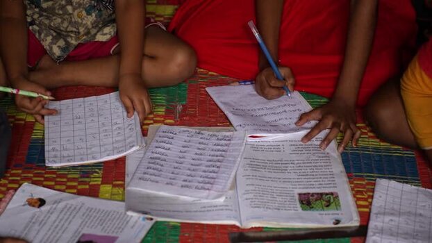 View of children writing in notebooks and studying Bangladesh.