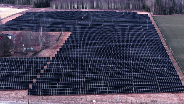 Aerial view of a large solar farm with rows of photovoltaic panels installed in a rural landscape in Latvia. Aerial view of a large solar farm with rows of photovoltaic panels installed in a rural landscape in Latvia.