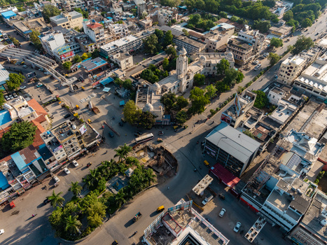 Aerial view of the urban landscape of Udaipur featuring historic buildings busy streets intersections and lush green trees in Udaipur Rajasthan India.