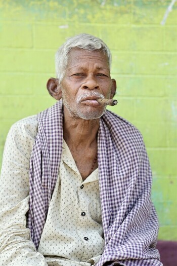 Odisha India 26 March 2026 View of an elderly man with weathered skin and silver hair contentedly smoking a cigar against a green backdrop. Odisha India 26 March 2026 View of an elderly man with weathered skin and silver hair contentedly smoking a cigar against a green backdrop.