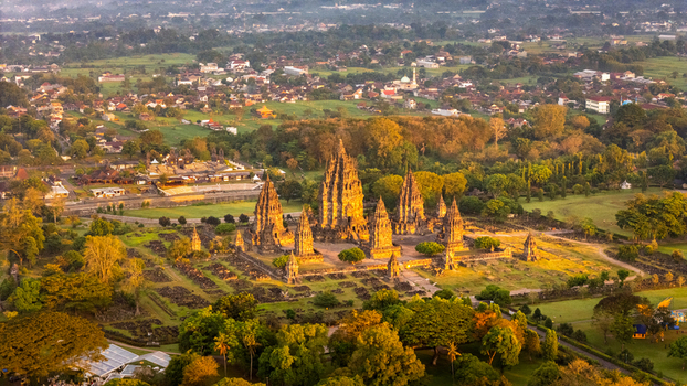 Aerial view of the Prambanan Temple complex with its iconic stone spires surrounded by lush green trees and a distant village Kecamatan Prambanan Daerah Istimewa Yogya Indonesia. Aerial view of the Prambanan Temple complex with its iconic stone spires surrounded by lush green trees and a distant village Kecamatan Prambanan Daerah Istimewa Yogya Indonesia.