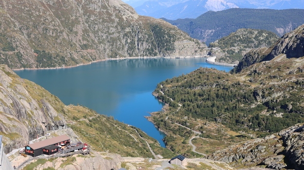 View of Lac du Vieux Emosson surrounded by rugged alpine mountains a dam and a small building in the foreground in Finhaut Valais Switzerland. View of Lac du Vieux Emosson surrounded by rugged alpine mountains a dam and a small building in the foreground in Finhaut Valais Switzerland.