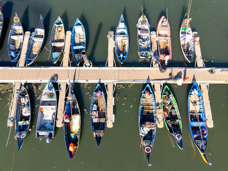 Aerial view of colorful boats lined up along the dock in the harbor their reflections shimmering on the water Porta de Abrigo da Torreira Aveiro Portugal. Aerial view of colorful boats lined up along the dock in the harbor their reflections shimmering on the water Porta de Abrigo da Torreira Aveiro Portugal.