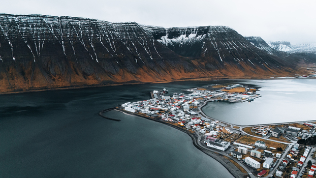 Aerial view of Ísafjörður nestled between still waters and rugged mountains a tapestry of red roofed buildings contrasting with the snow dusted peaks Ísafjörður Iceland. Aerial view of Ísafjörður nestled between still waters and rugged mountains a tapestry of red roofed buildings contrasting with the snow dusted peaks Ísafjörður Iceland.