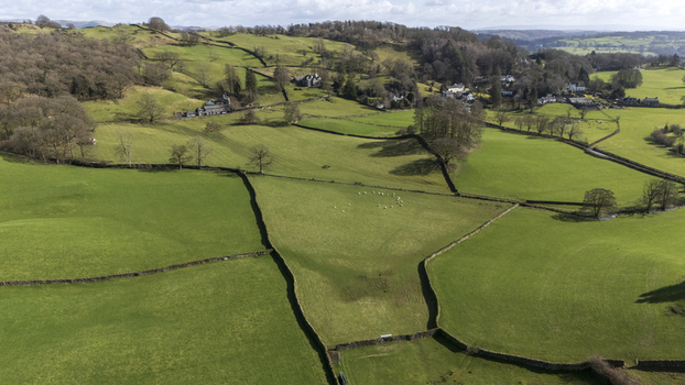 Aerial view of vibrant green fields divided by dark stone walls create a patchwork across the rolling hills England United Kingdom. Aerial view of vibrant green fields divided by dark stone walls create a patchwork across the rolling hills England United Kingdom.