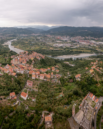 Aerial view of the historic village of Vezzano Ligure with terracotta rooftops and stone architecture surrounded by green hills and a winding river in Vezzano Ligure Liguria Italy.