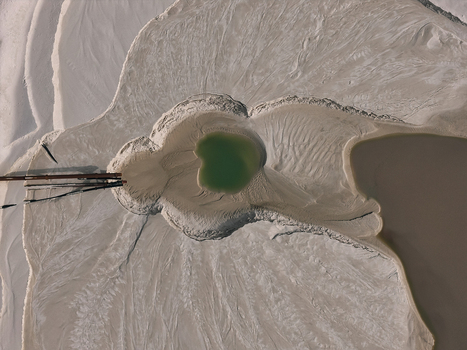 Aerial view of a sand extraction site featuring a vibrant green pool surrounded by textured sediment patterns and industrial pipes in Dulmen North Rhine Westphalia Germany. Aerial view of a sand extraction site featuring a vibrant green pool surrounded by textured sediment patterns and industrial pipes in Dulmen North Rhine Westphalia Germany.