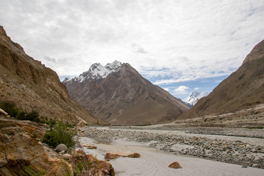 View of K2 Base Camp surrounded by rugged mountain peaks a rocky riverbed and a cloudy sky in Ghakhar Gilgit Pakistan. View of K2 Base Camp surrounded by rugged mountain peaks a rocky riverbed and a cloudy sky in Ghakhar Gilgit Pakistan.