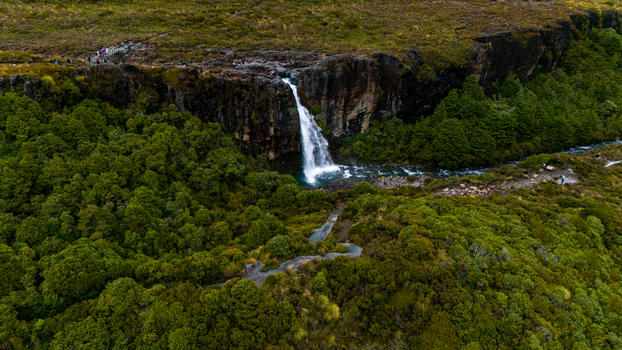 Aerial view of the powerful cascade of Taranaki Falls plunges from dark cliffs into vibrant green forests a stunning contrast of nature s raw beauty Taranaki Falls New Zealand. Aerial view of the powerful cascade of Taranaki Falls plunges from dark cliffs into vibrant green forests a stunning contrast of nature s raw beauty Taranaki Falls New Zealand.