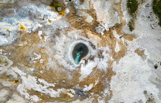Aerial view of Hveravellir geothermal area featuring a steaming hot spring with turquoise water surrounded by mineral crusts and volcanic terrain in Hunabyggd Iceland. Aerial view of Hveravellir geothermal area featuring a steaming hot spring with turquoise water surrounded by mineral crusts and volcanic terrain in Hunabyggd Iceland.