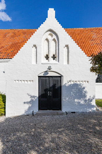 View of the white church building with stepped gable and black doors in Hindsholm Kerteminde Municipality Denmark. View of the white church building with stepped gable and black doors in Hindsholm Kerteminde Municipality Denmark.