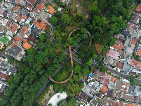 Aerial view of Tebet Eco Park featuring its winding infinity bridge surrounded by lush trees and dense urban residential neighborhoods in Kecamatan Tebet Daerah Khusus Ibukota Indonesia. Aerial view of Tebet Eco Park featuring its winding infinity bridge surrounded by lush trees and dense urban residential neighborhoods in Kecamatan Tebet Daerah Khusus Ibukota Indonesia.