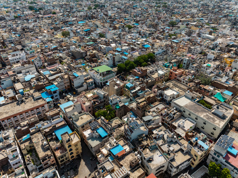 Aerial view of the dense urban landscape of Udaipur featuring a complex network of traditional rooftops narrow streets and residential buildings in Udaipur Rajasthan India.