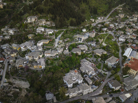 Aerial view of the historic stone houses and slate rooftops of Gjirokaster nestled in the mountainous landscape of Gjirokaster Gjirokaster County Albania. Aerial view of the historic stone houses and slate rooftops of Gjirokaster nestled in the mountainous landscape of Gjirokaster Gjirokaster County Albania.