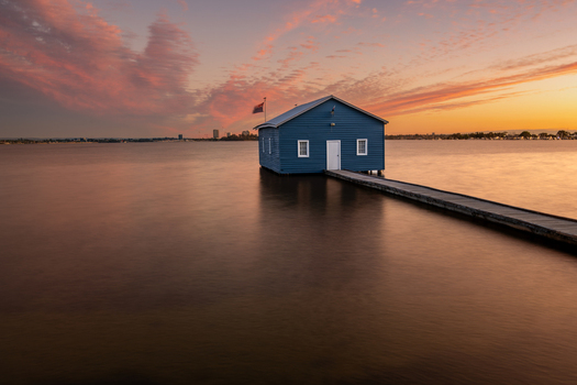 View of the iconic Blue Boat House on the Swan River at sunset with a wooden jetty and calm water in Crawley Western Australia Australia. View of the iconic Blue Boat House on the Swan River at sunset with a wooden jetty and calm water in Crawley Western Australia Australia.