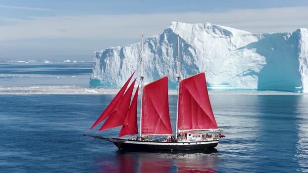 Aerial view of sailboat with red sails near iceberg Greenland. Aerial view of sailboat with red sails near iceberg Greenland.