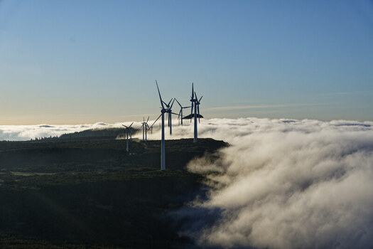 Aerial view of wind turbines standing on the ridge of Bica da Cana peak above a sea of clouds in Funchal Madeira Portugal.