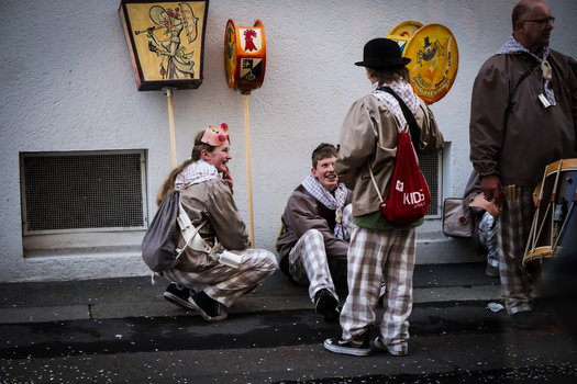 Basel Switzerland 10 March 2025 View of costumed figures in checkered patterns sit on the wet ground by a white wall while holding lanterns during Fasnacht. Basel Switzerland 10 March 2025 View of costumed figures in checkered patterns sit on the wet ground by a white wall while holding lanterns during Fasnacht.