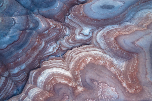 Aerial view of swirling layered rock formations create a mesmerizing abstract landscape of earthy reds and cool blues Hanksville Utah United States. Aerial view of swirling layered rock formations create a mesmerizing abstract landscape of earthy reds and cool blues Hanksville Utah United States.