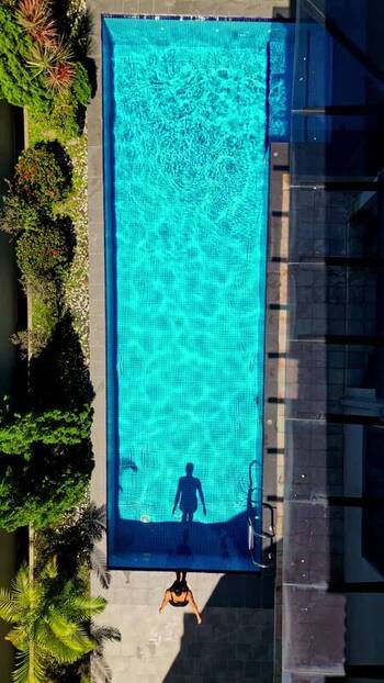 Aerial view of a person by a turquoise swimming pool Malaysia.