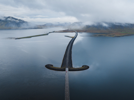 Aerial view of a road stretching through calm waters towards distant mountains under a cloudy sky Snæfellsnes Eyja og Miklaholtshreppur Iceland. Aerial view of a road stretching through calm waters towards distant mountains under a cloudy sky Snæfellsnes Eyja og Miklaholtshreppur Iceland.