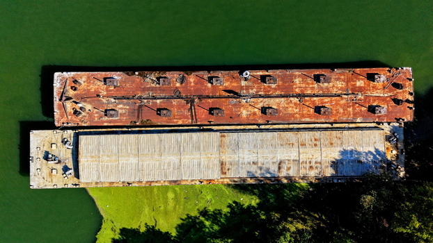 Aerial view of two industrial barges moored on the Danube river one with a rusted metal deck and the other with a covered cargo hold in Smederevo Podunavlje District Serbia.