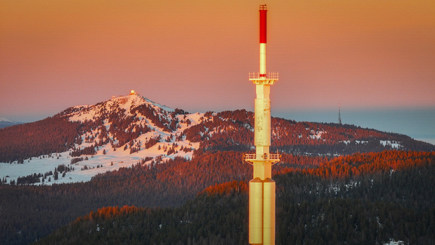 Aerial view of the Col de la Faucille telecommunications tower with snow covered Jura Mountains under a golden sunset sky Gex Auvergne Rhone Alpes France. Aerial view of the Col de la Faucille telecommunications tower with snow covered Jura Mountains under a golden sunset sky Gex Auvergne Rhone Alpes France.
