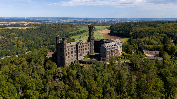 Aerial view of Schaumburg Castle surrounded by dense green forests and rolling hills in Balduinstein Rheinland Pfalz Germany. Aerial view of Schaumburg Castle surrounded by dense green forests and rolling hills in Balduinstein Rheinland Pfalz Germany.