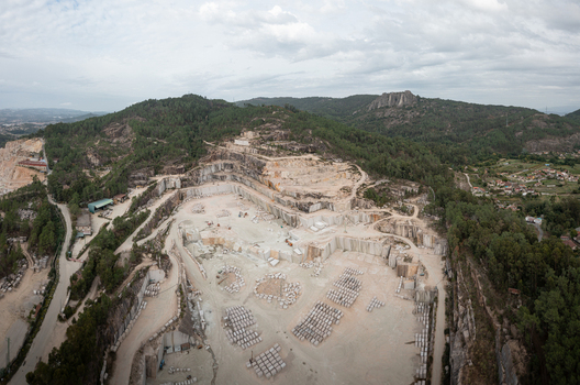 Aerial view of the Cantera Porrino granite quarry featuring large stone blocks excavation terraces and surrounding forested hills in O Porrino Pontevedra Spain. Aerial view of the Cantera Porrino granite quarry featuring large stone blocks excavation terraces and surrounding forested hills in O Porrino Pontevedra Spain.