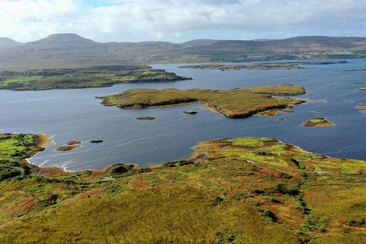 Aerial view of the rugged coastal landscape of the Isle of Skye featuring dark waters small islands and rolling hills under a cloudy sky Isle of Skye Scotland United Kingdom. Aerial view of the rugged coastal landscape of the Isle of Skye featuring dark waters small islands and rolling hills under a cloudy sky Isle of Skye Scotland United Kingdom.