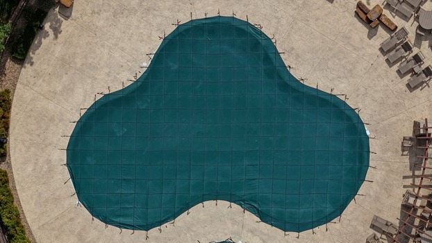 Aerial view of a swimming pool covered with a green safety net surrounded by a stone patio Golden Colorado United States.