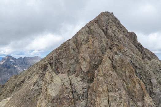 Aerial view of the rugged rocky peak of Mount Sneffels in the San Juan Mountains under a cloudy sky in Ouray County Colorado United States. Aerial view of the rugged rocky peak of Mount Sneffels in the San Juan Mountains under a cloudy sky in Ouray County Colorado United States.